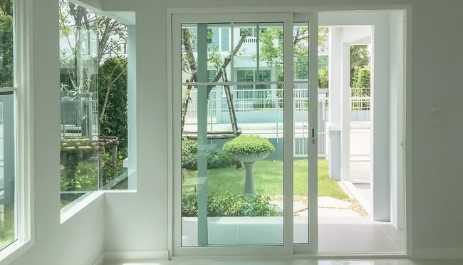 Bright white interior with a sliding glass door and window, view of a yard with greenery.