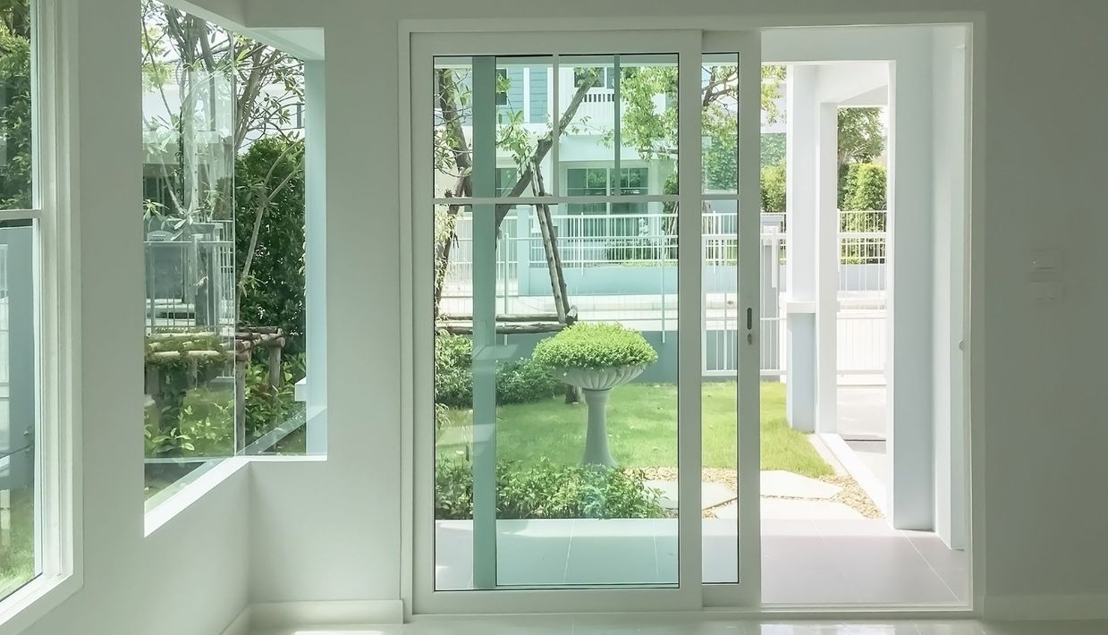 Bright white interior with a sliding glass door and window, view of a yard with greenery.