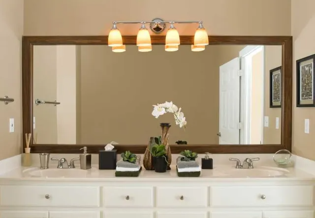 Bathroom with large framed mirror, double sinks, light fixture, and decor.