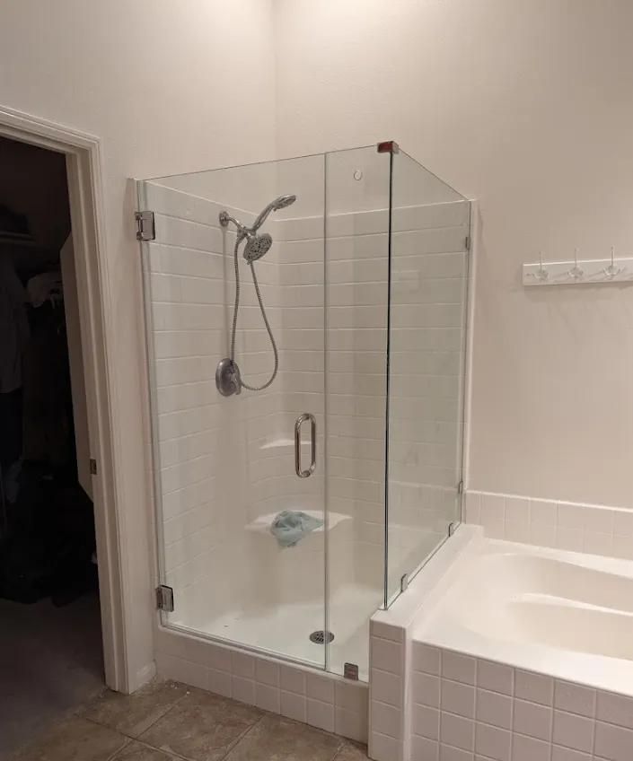 A modern bathroom with a glass shower enclosure, a built-in tub, and white tiling.