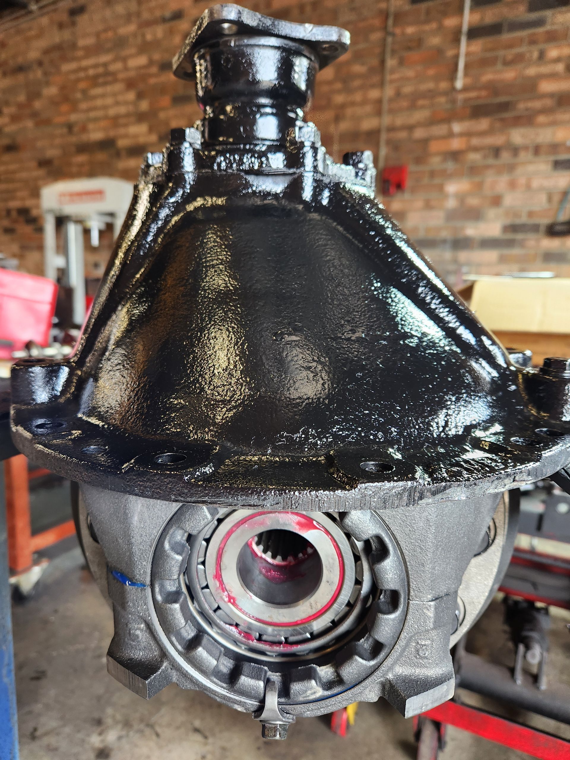 A close up of a gearbox in a garage with a brick wall in the background.