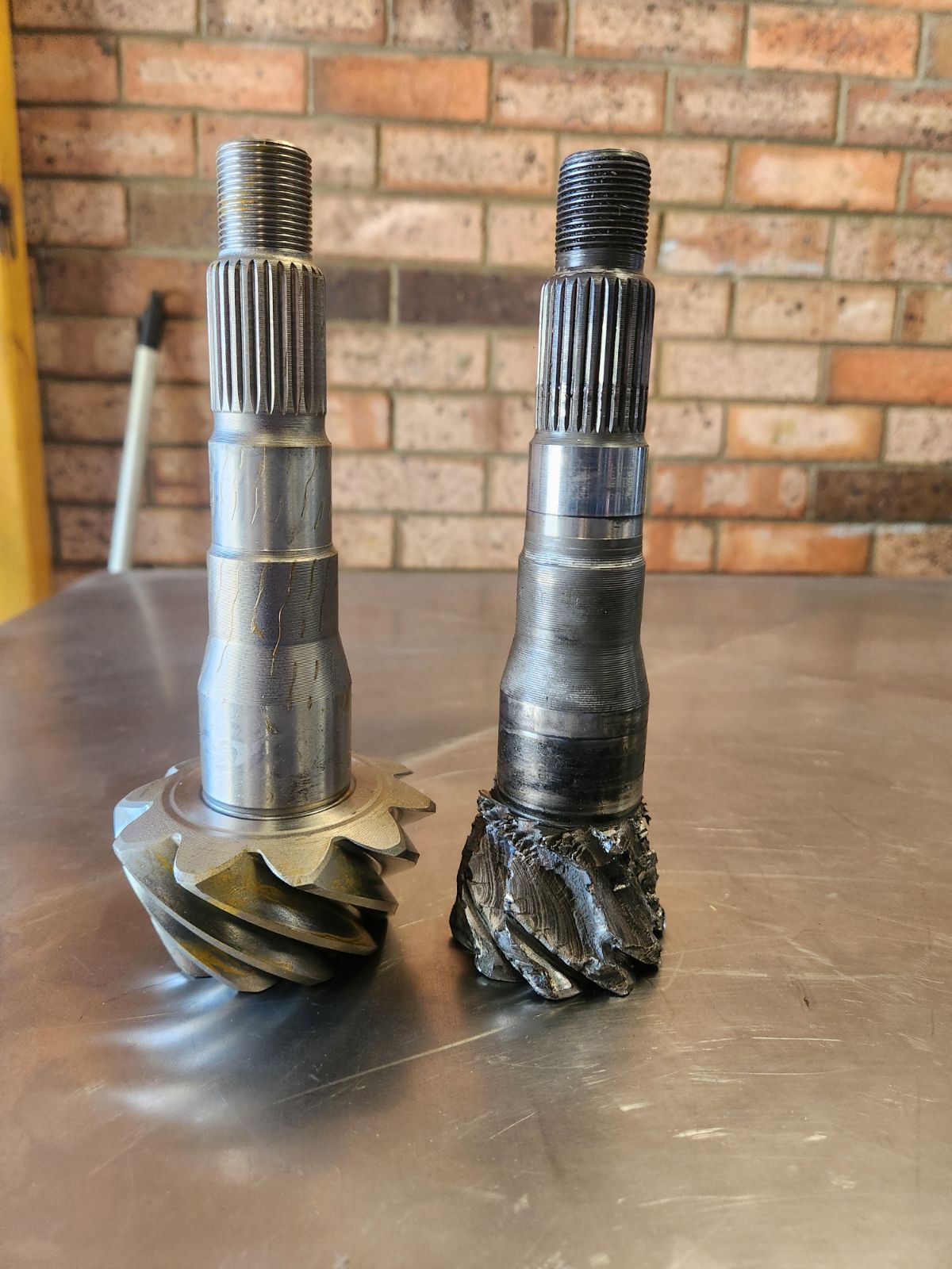 Two gears are sitting on a metal table in front of a brick wall.
