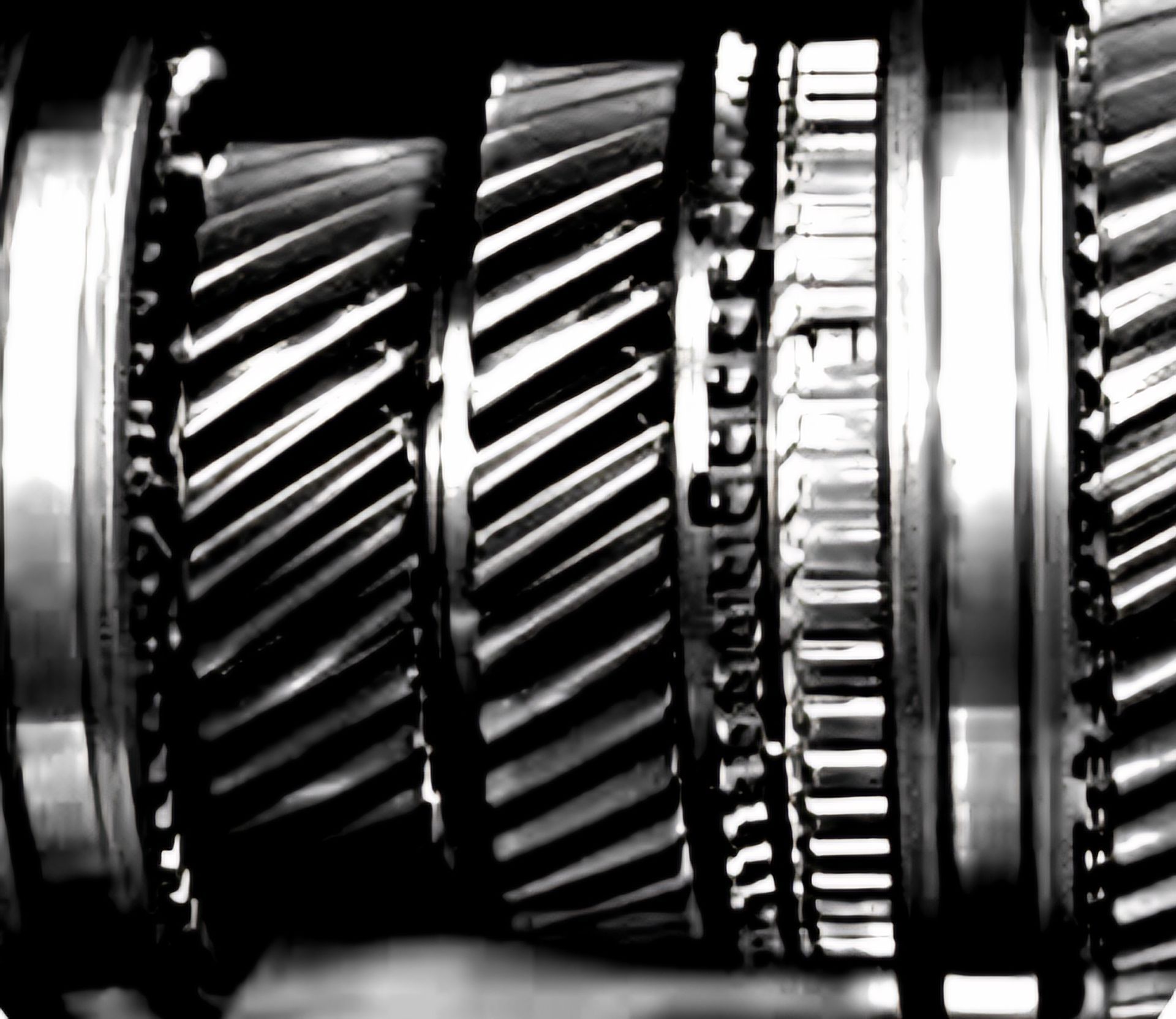 A close up of a row of metal gears on a black background.