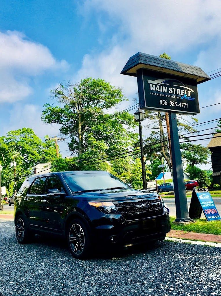 Dark SUV parked near a Main Street sign under a blue sky. | Main Street Auto