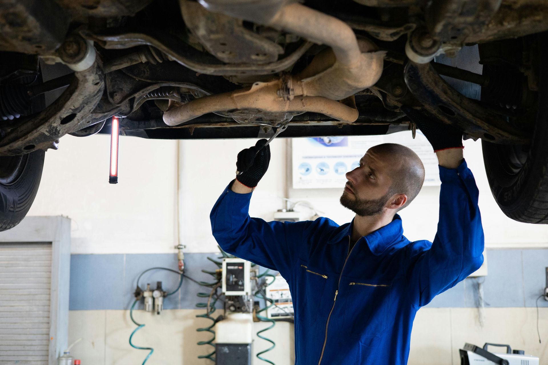 A man is working under a car in a garage.