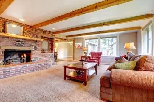 Cozy living room with brick fireplace, exposed wood beams, and a plush sofa.