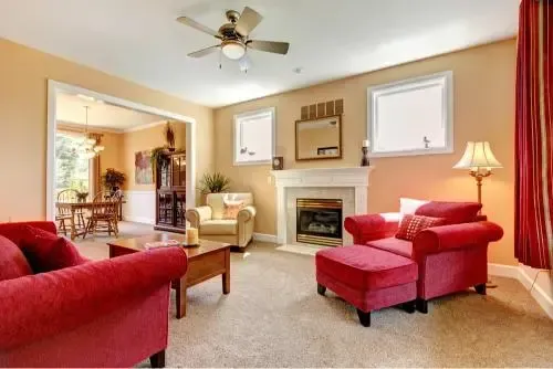 Cozy living room with red furniture, fireplace, and beige walls, connected to dining area.