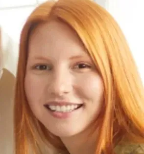Young woman with long red hair smiling at the camera.