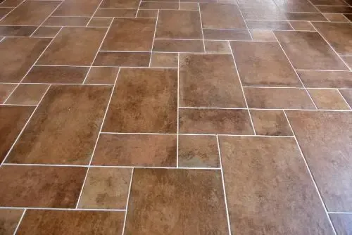 Brown tile floor with white grout in a random pattern.