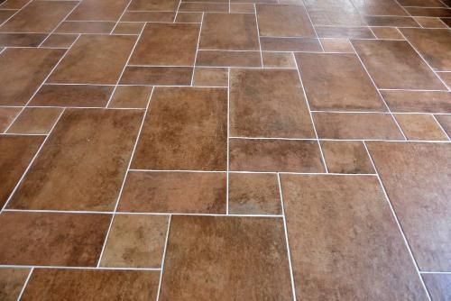 Brown tile floor with white grout in a random pattern.