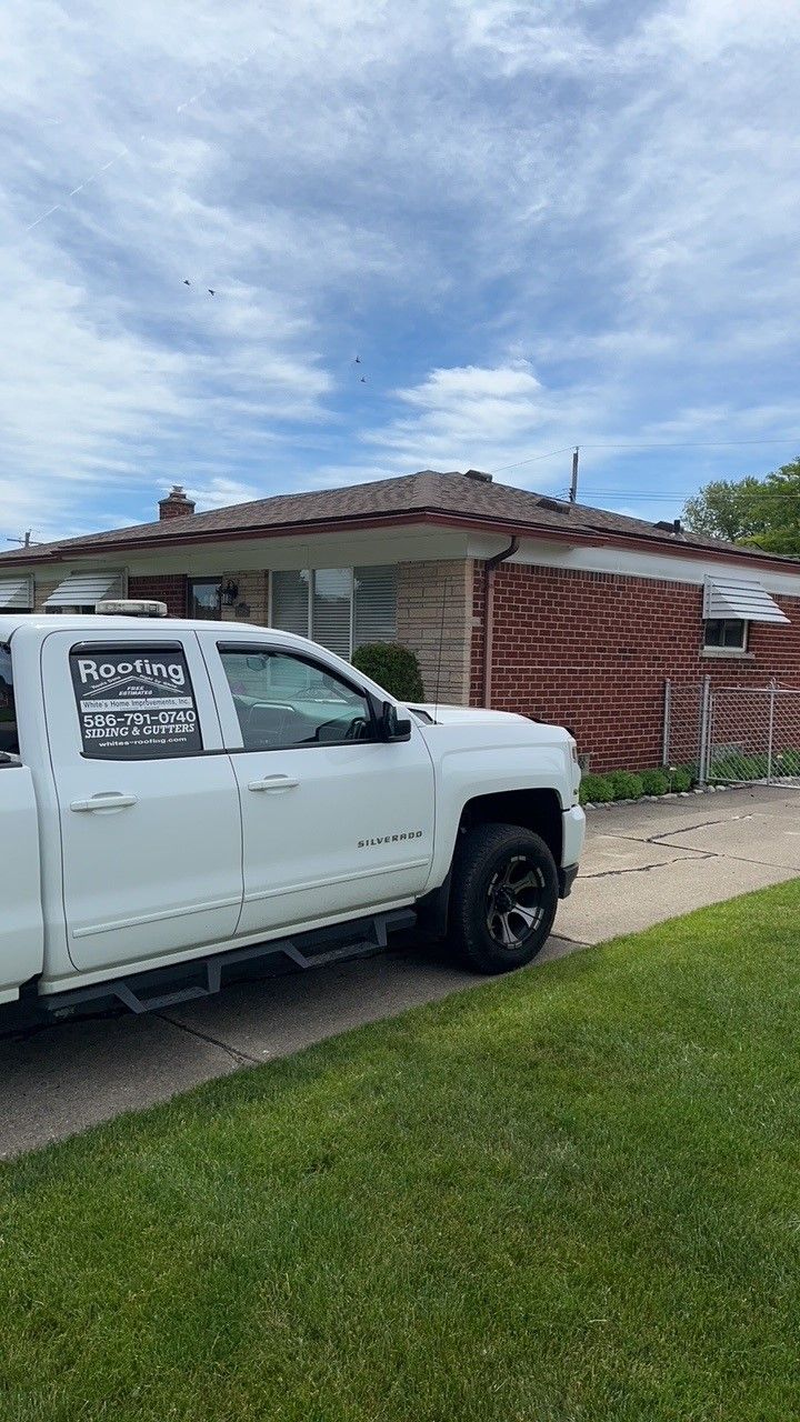 A white truck is parked in front of a brick house.