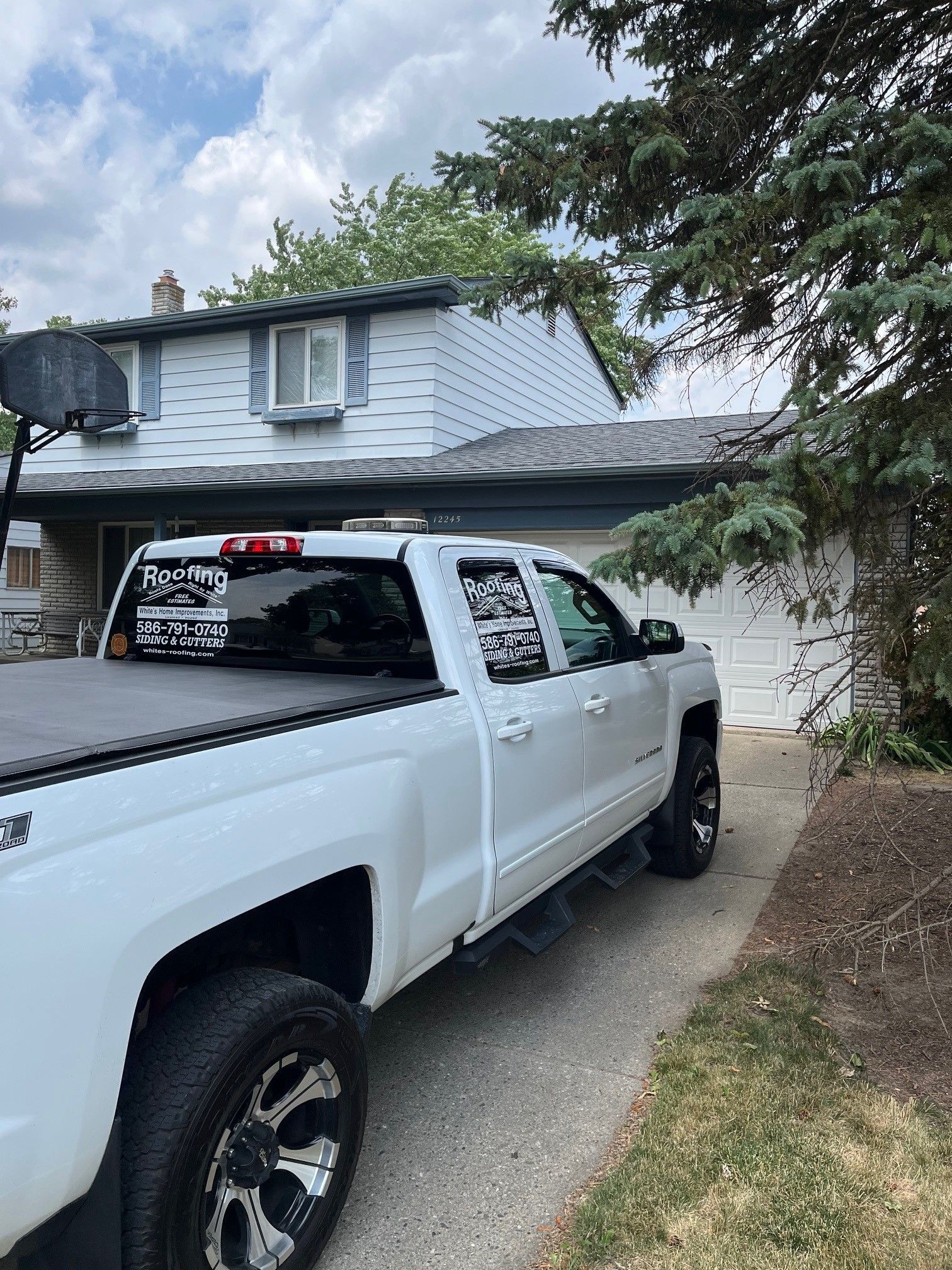 A white truck is parked in front of a house.