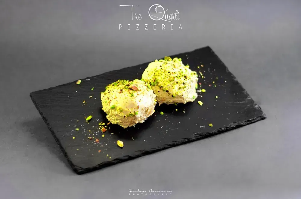 Due palline di dessert con pistacchi su una lavagna nera.