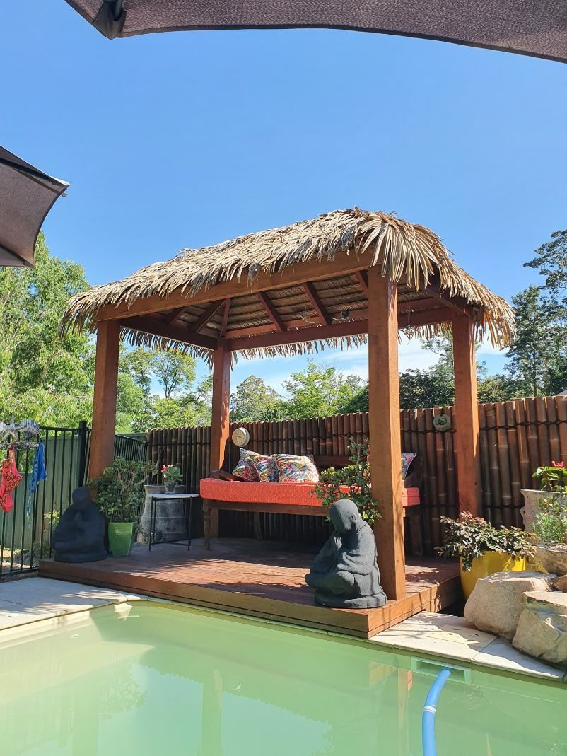 A Gazebo With a Thatched Roof Next to a Swimming Pool — Offcut Carpentry In Murwillumbah, NSW