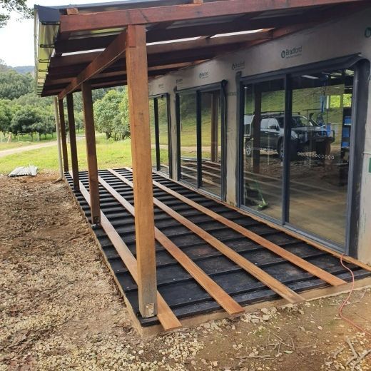 A House With a Lot of Windows and a Wooden Deck Underneath It — Offcut Carpentry In Murwillumbah, NSW