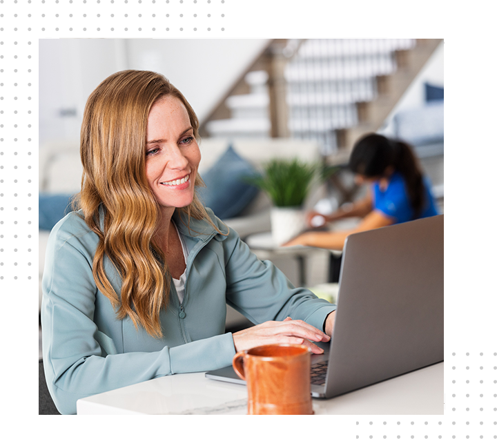 Woman cleaning cabinets as man works on laptop.