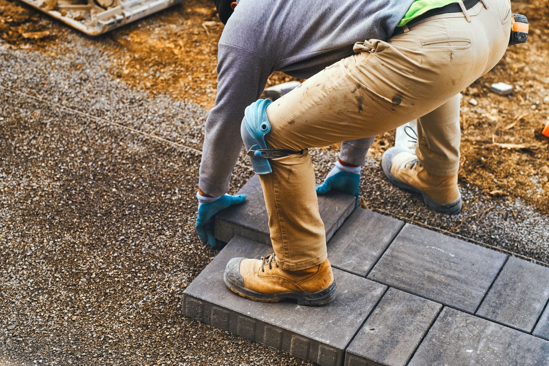 Residential paving contractor installing concrete pavers during a home driveway construction project.