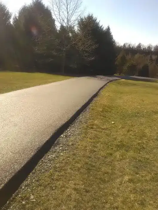 a road going through a grassy field with trees in the background — Allentown, PA — Diehl Paving Inc.