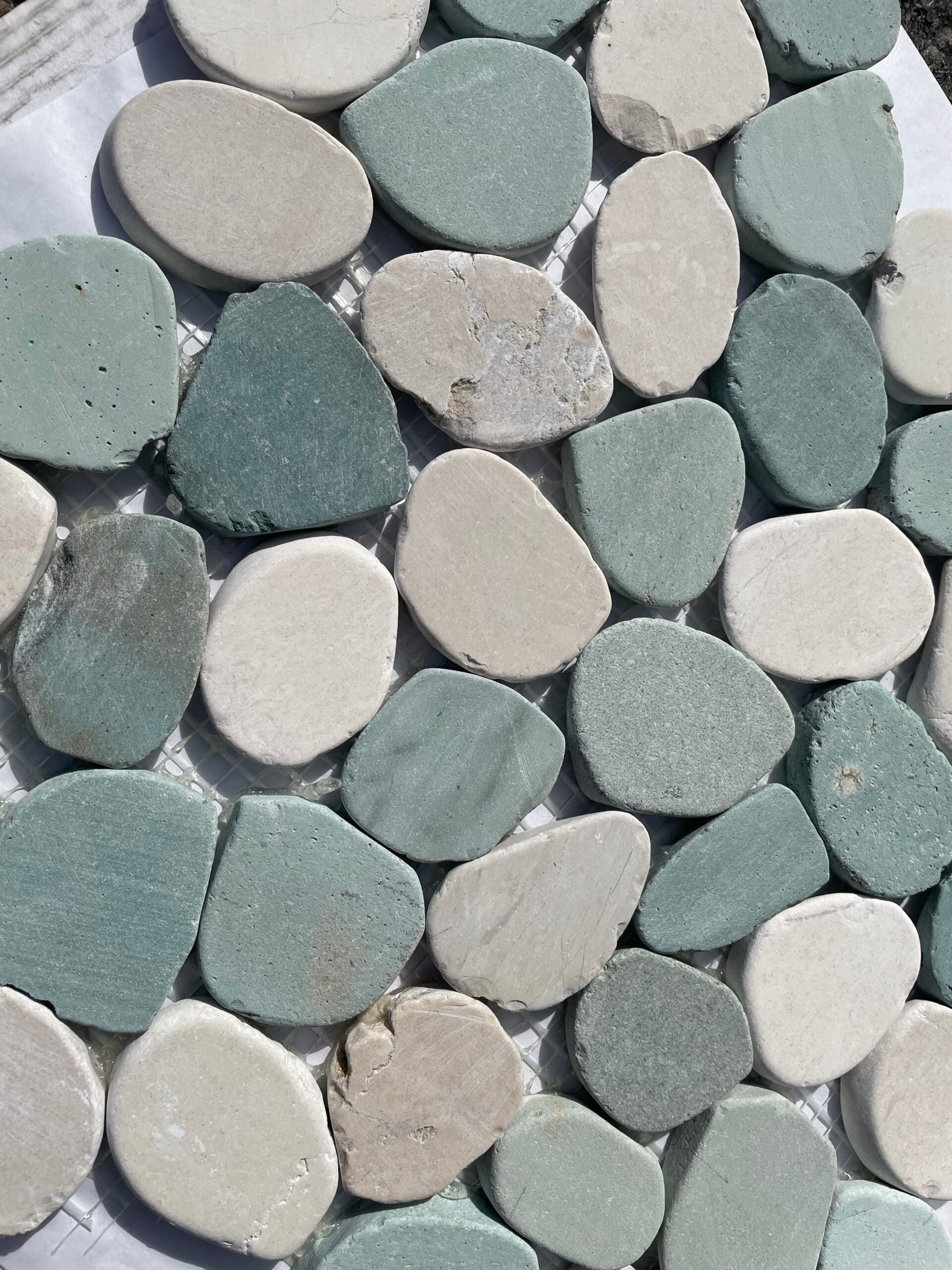 Natural pebble mosaic in coastal tones, perfect for walk-in showers and outdoor floors.