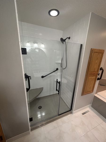 A bathroom with a walk in shower with a glass door.