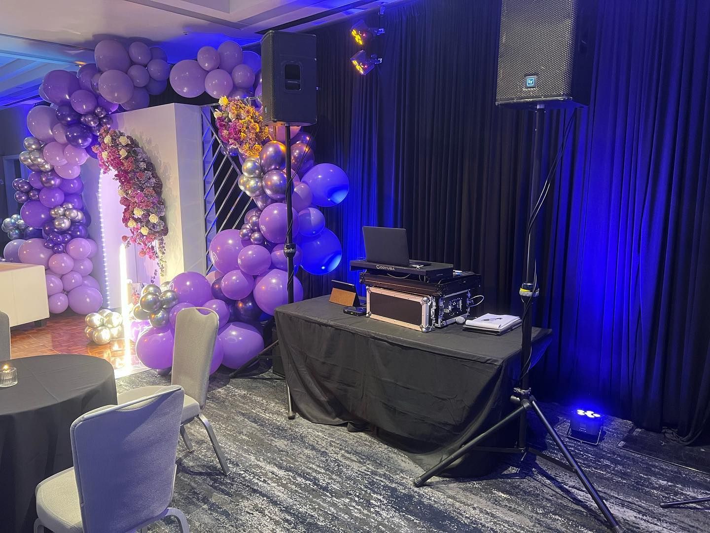A room decorated with purple balloons and a dj booth.
