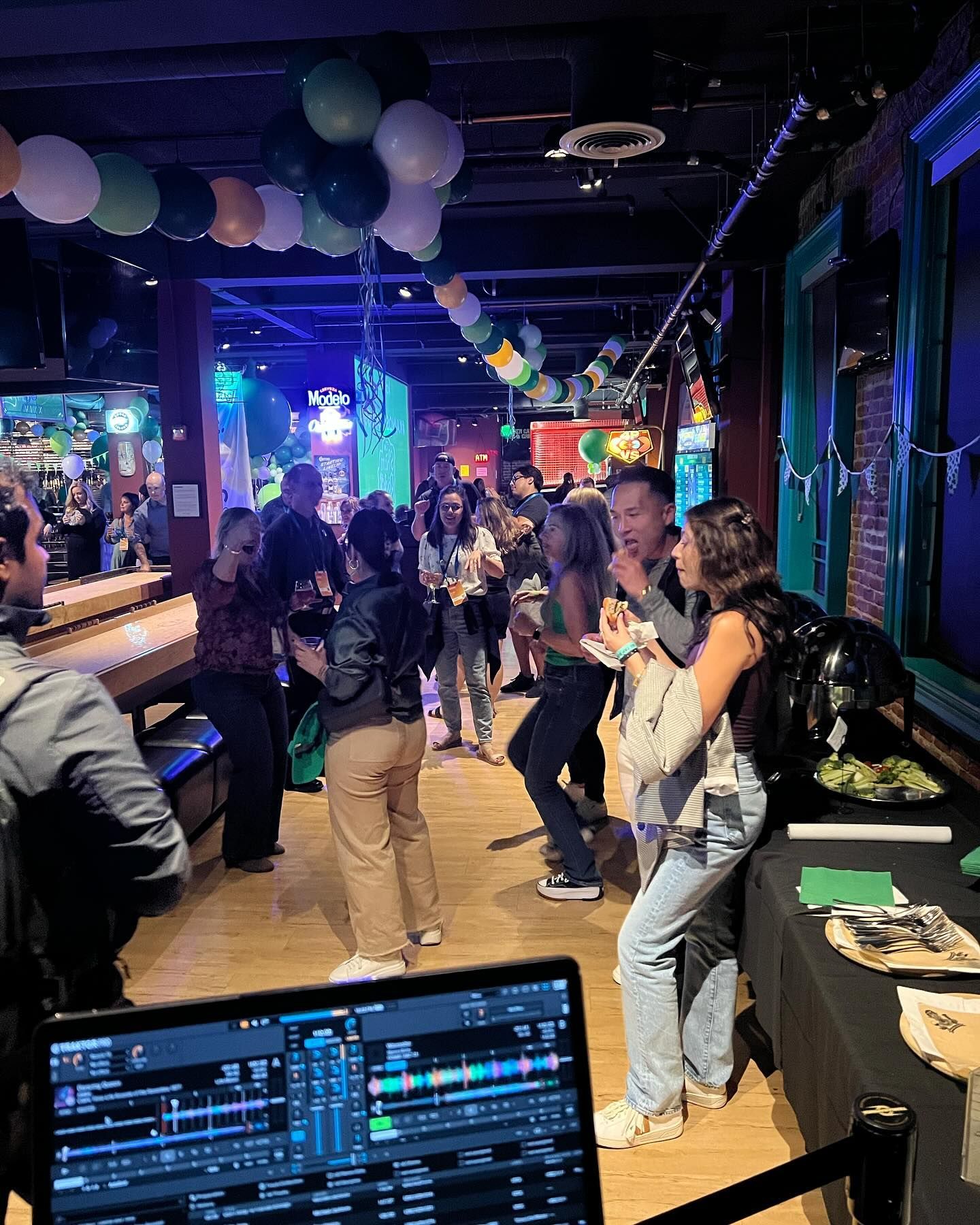 A group of people are dancing in a room with balloons hanging from the ceiling.