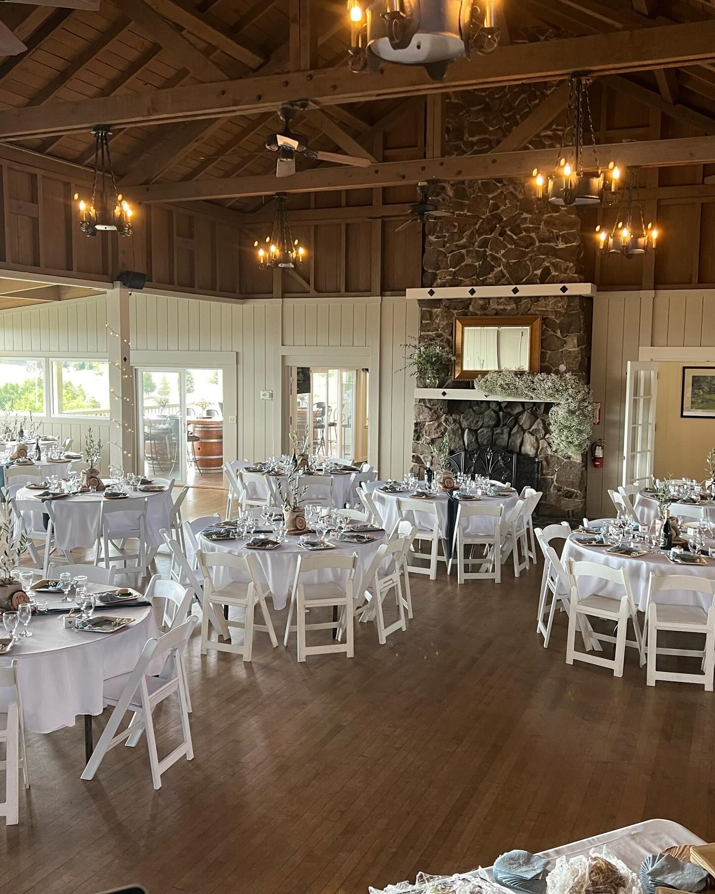 A large room with tables and chairs set up for a wedding reception