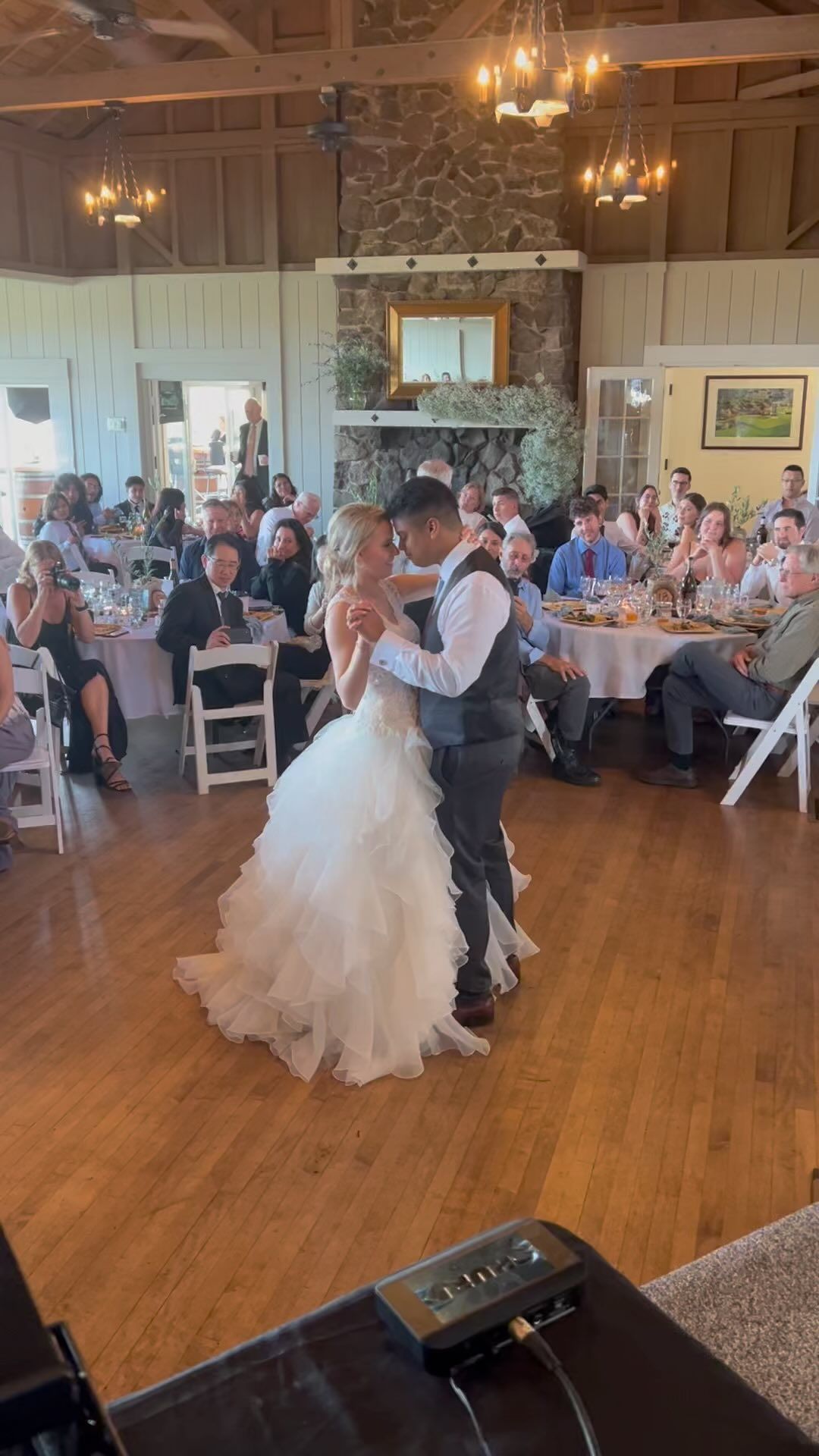 A bride and groom are dancing at their wedding reception in front of a crowd.