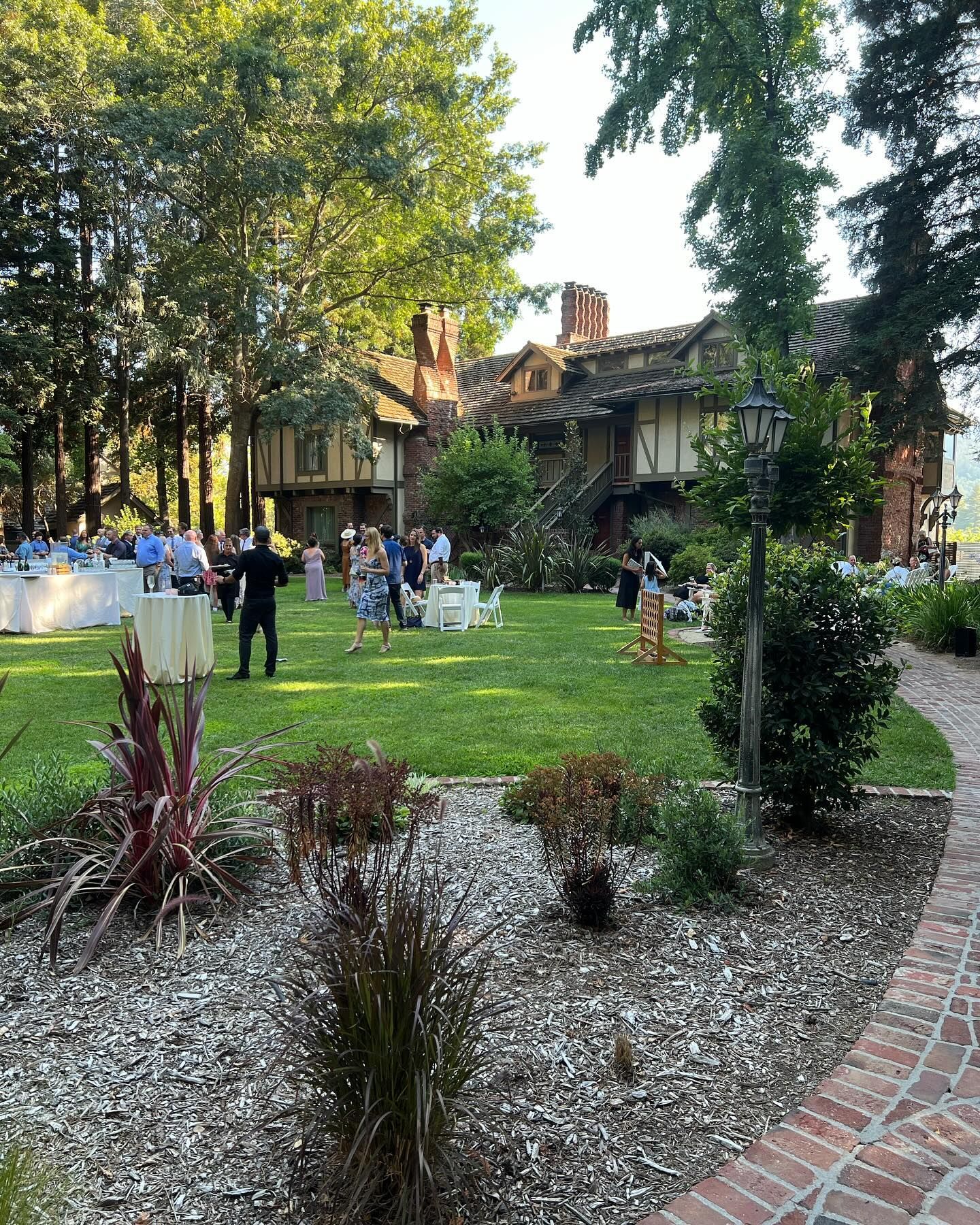 A group of people are standing in a grassy field in front of a large building.