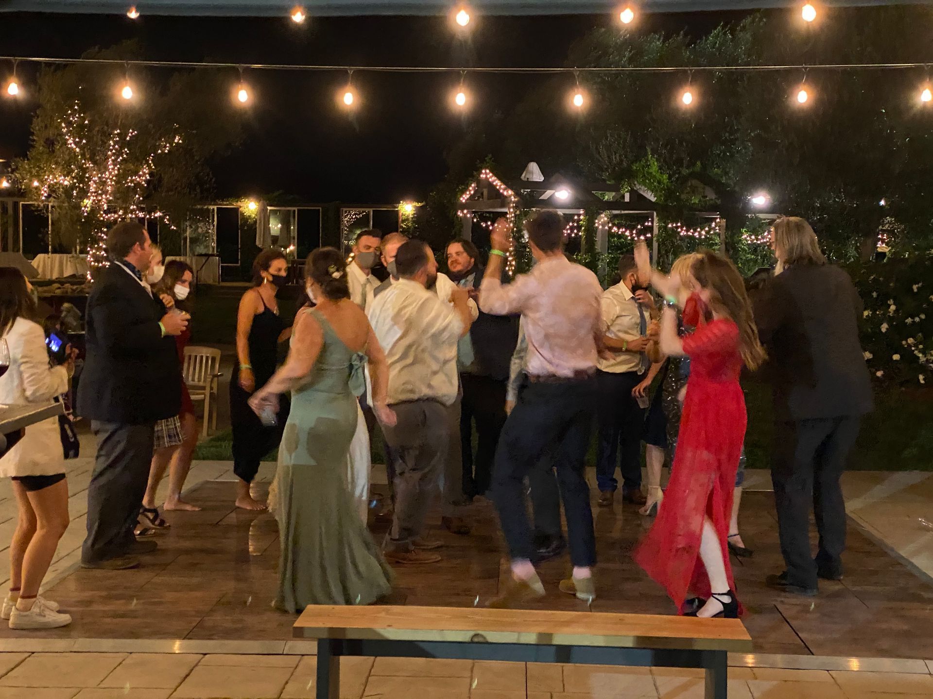 A group of people are dancing at a wedding reception.