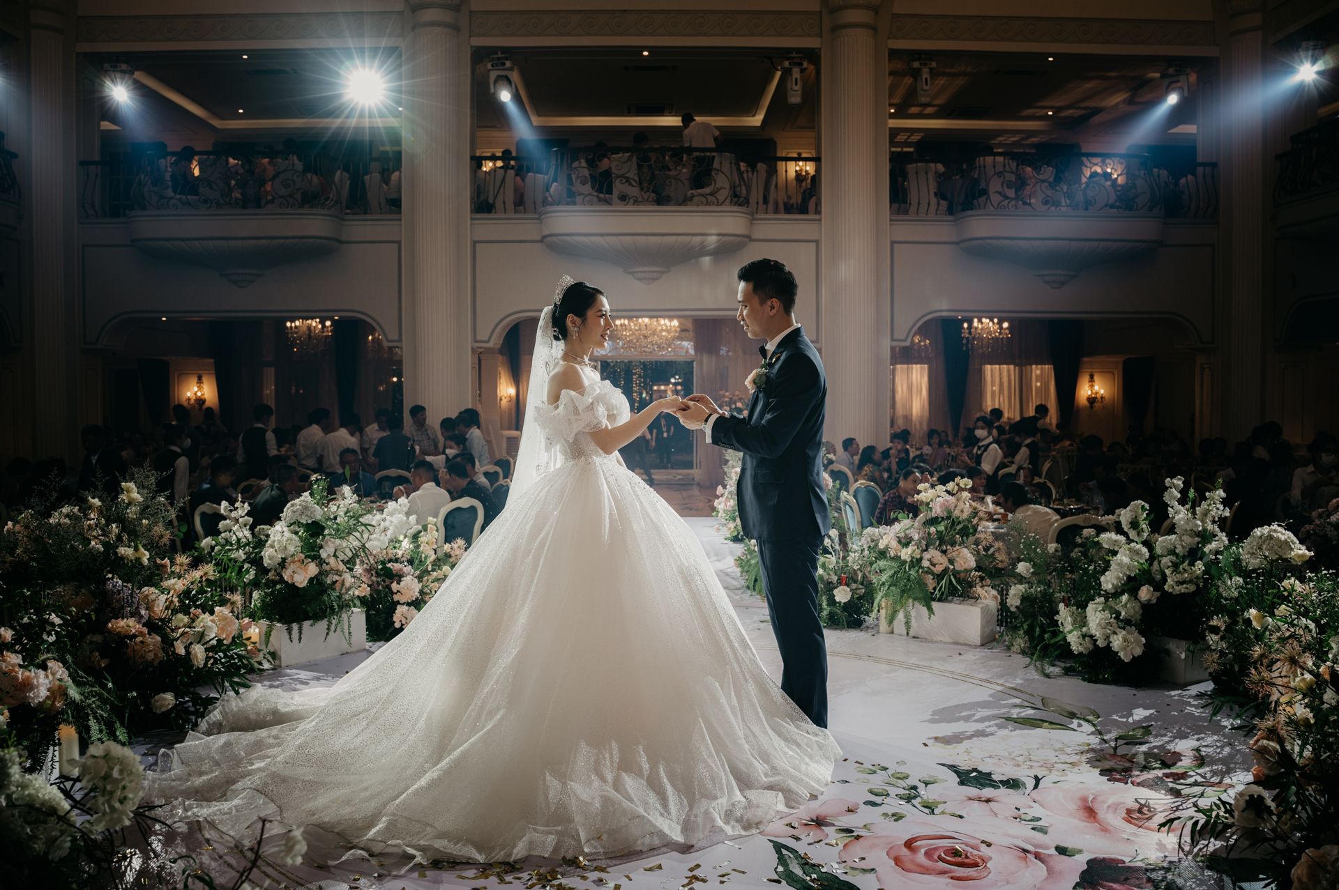 A bride and groom are holding hands during their wedding ceremony in front of a crowd.