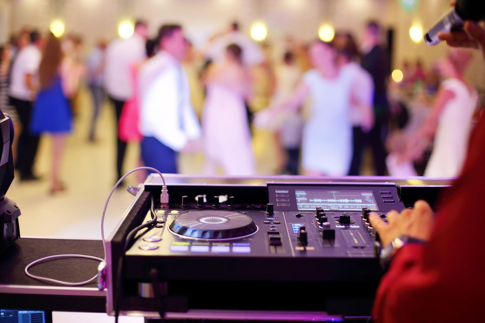 A group of people are dancing in a large room with a laptop in the foreground