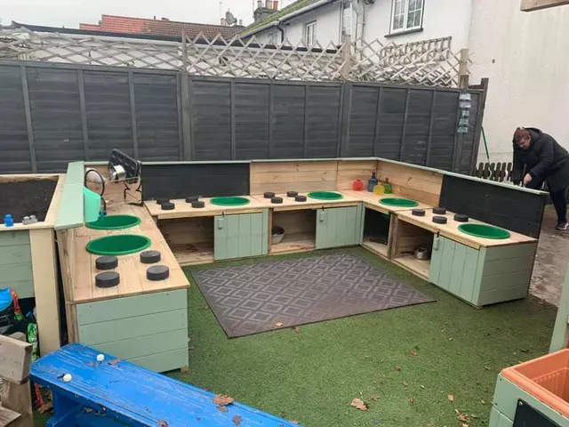 A Childrens play kitchen outside on green Astroturf