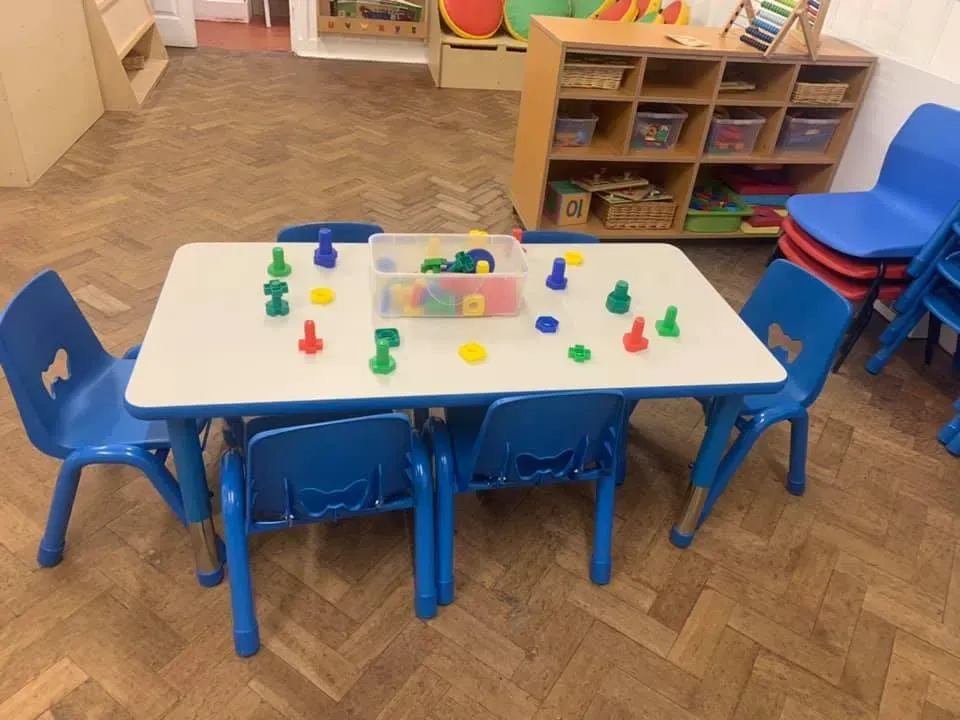 A white table with blue chairs and toys on it