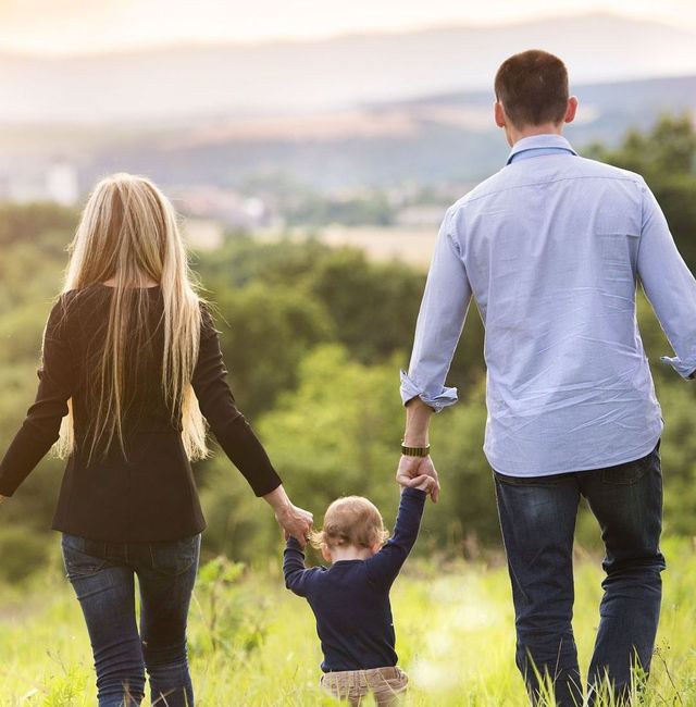 A family is walking through a field holding hands.
