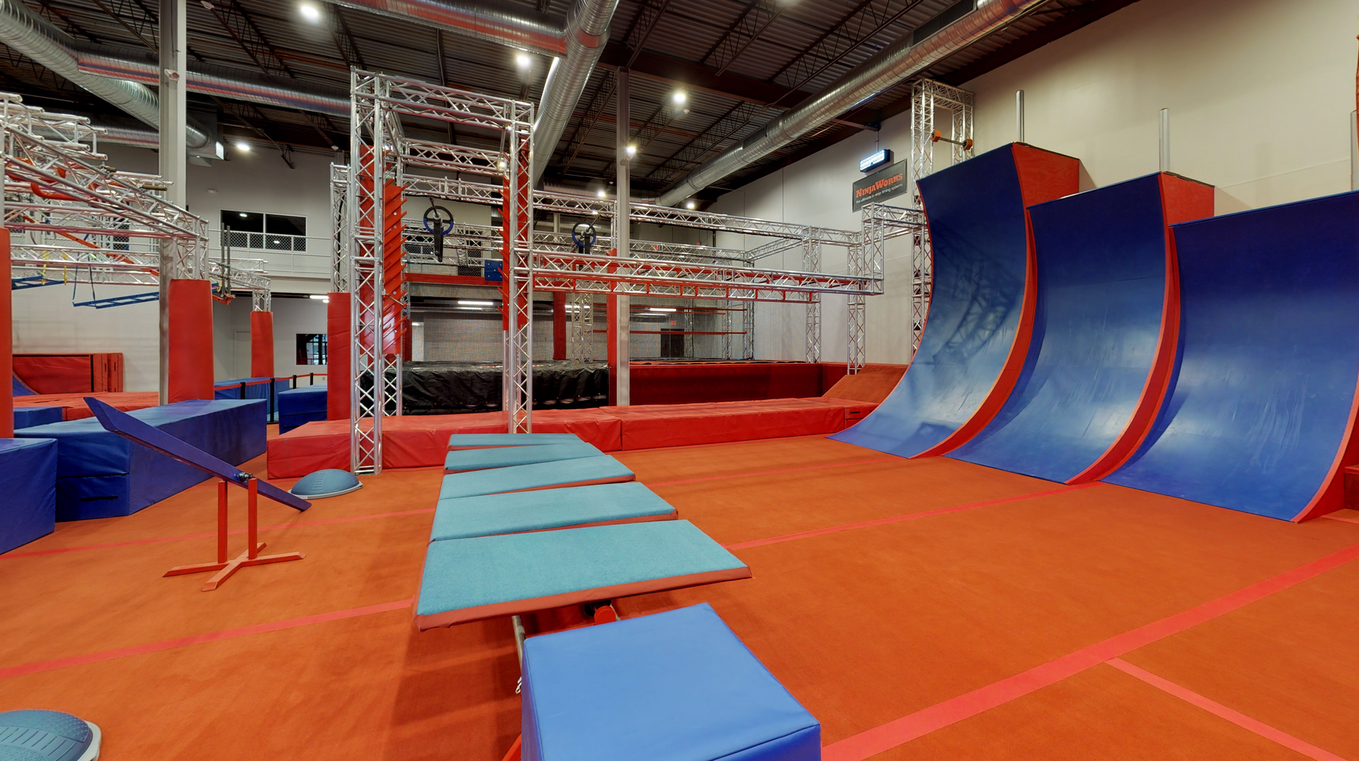 Indoor obstacle course with red and blue structures for fitness and recreation.
