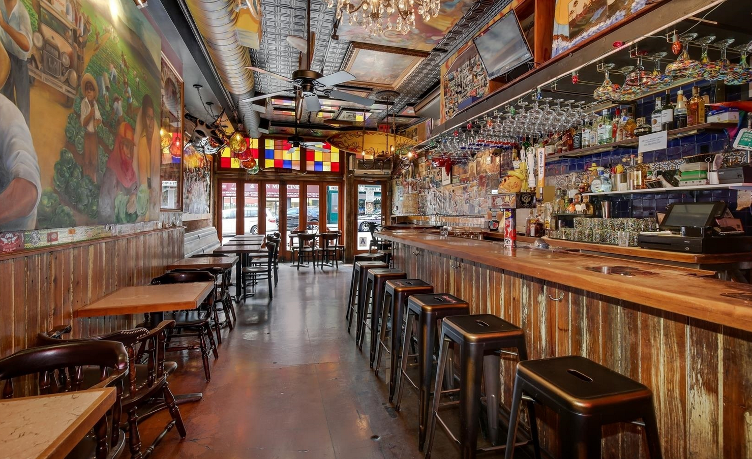 Interior view of a rustic bar with wooden walls, tables, and a long counter.
