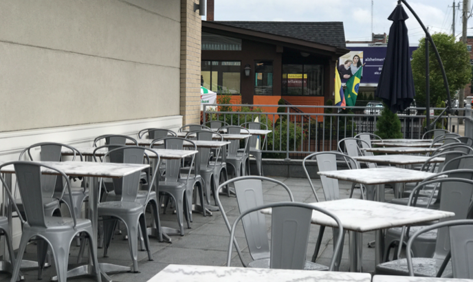 Outdoor patio with metal chairs and tables, in front of a restaurant.
