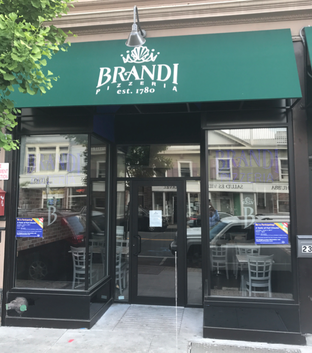 Brandi Pizzeria storefront with green awning, glass windows, and the address 23.