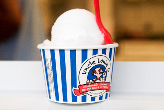 Ice cream in a blue and white striped cup with a red spoon. Uncle Louie G's logo visible.