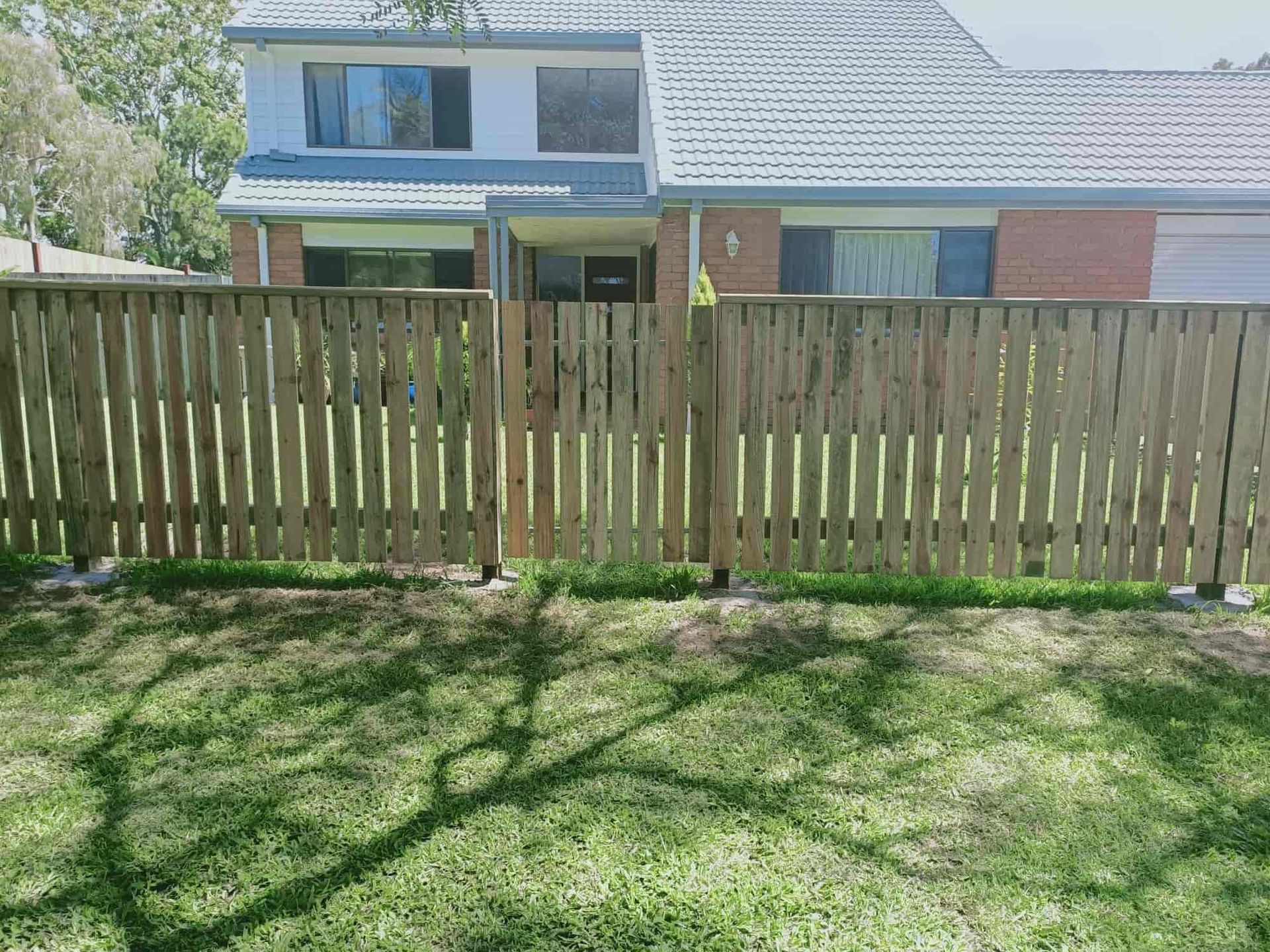Wooden fence in front of a house, cast shadow of tree on the grass. — Quality Fences 4 U in Gympie, QLD