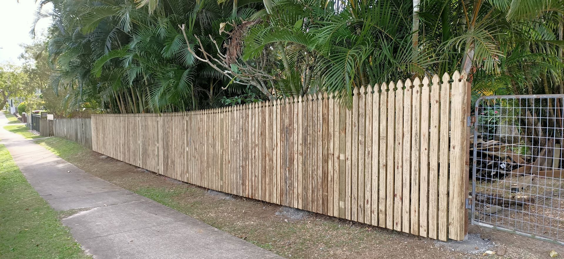 Wooden picket fence along a sidewalk, trees in background — Quality Fences 4 U in Gympie, QLD