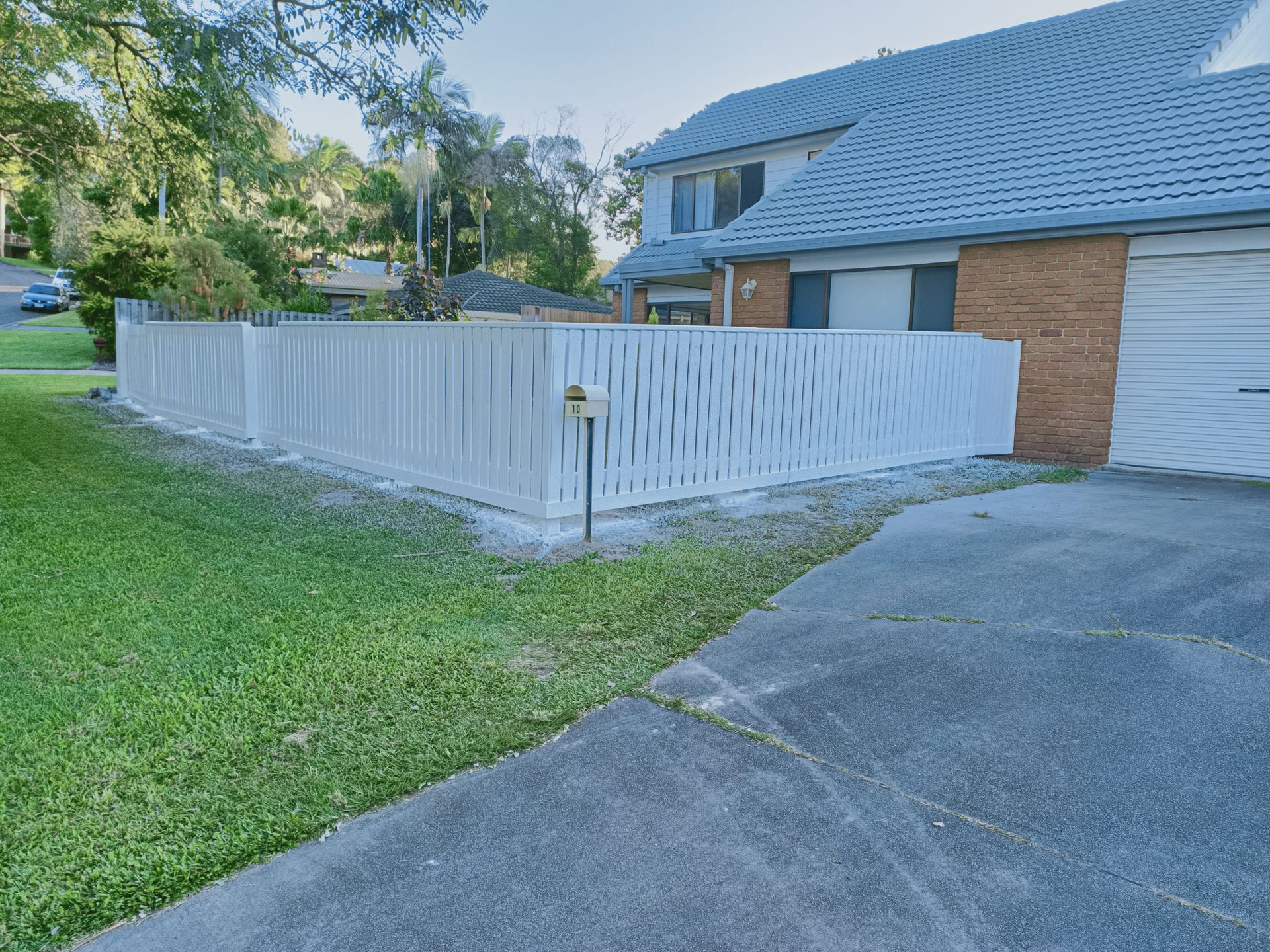 White picket fence in front of a house, beside a driveway and green grass — Quality Fences 4 U in Gympie, QLD