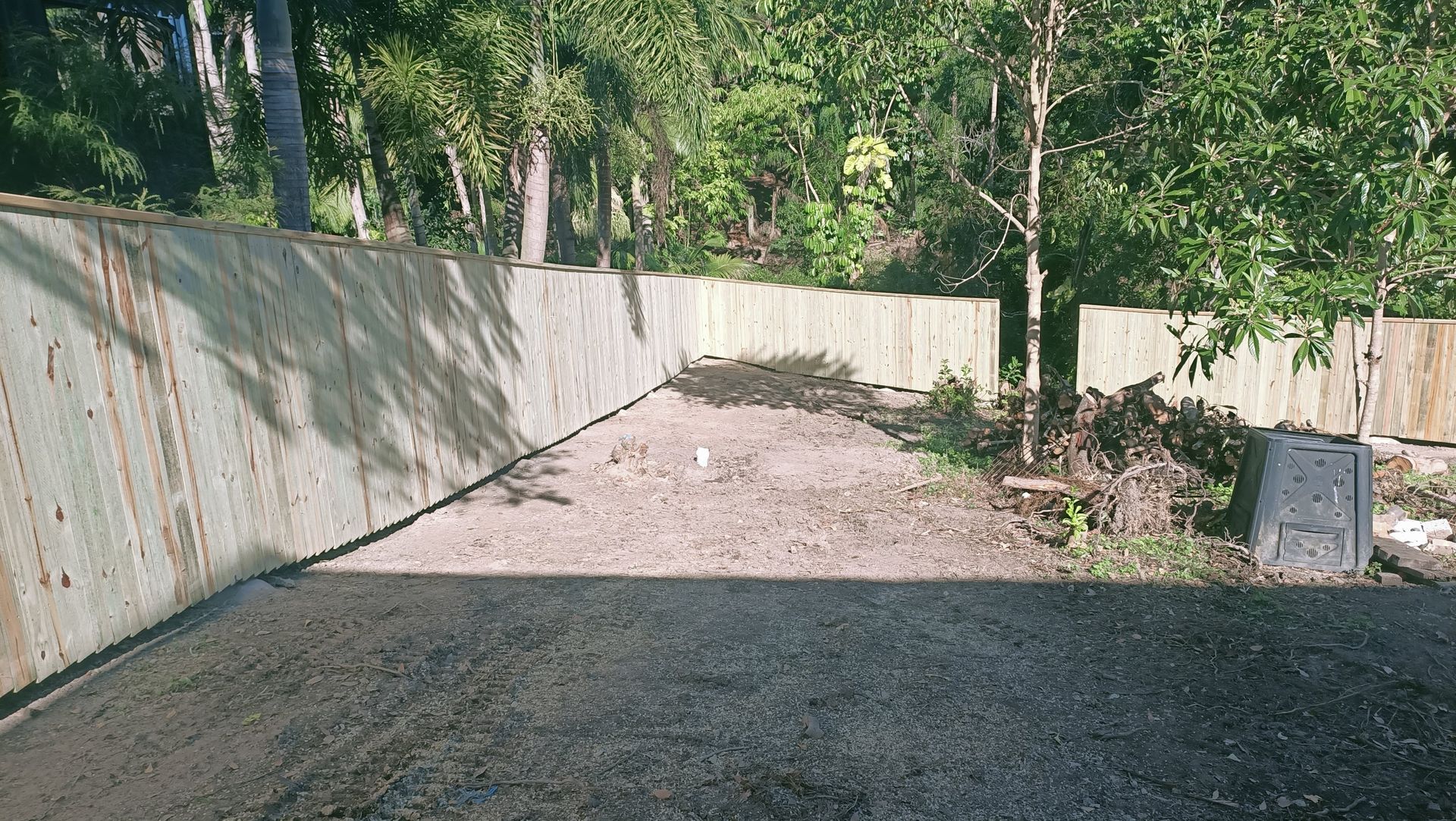 Concrete retaining wall with gravel in front, trees in the background, lit by sunlight — Quality Fences 4 U in Gympie, QLD