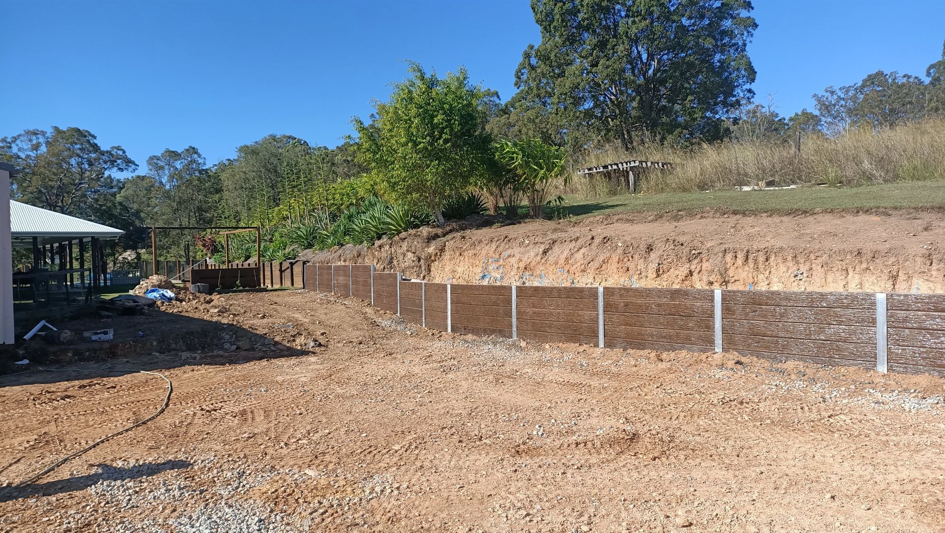 A new construction site with a retaining wall made of timber. Brown dirt and gravel — Quality Fences 4 U in Gympie, QLD