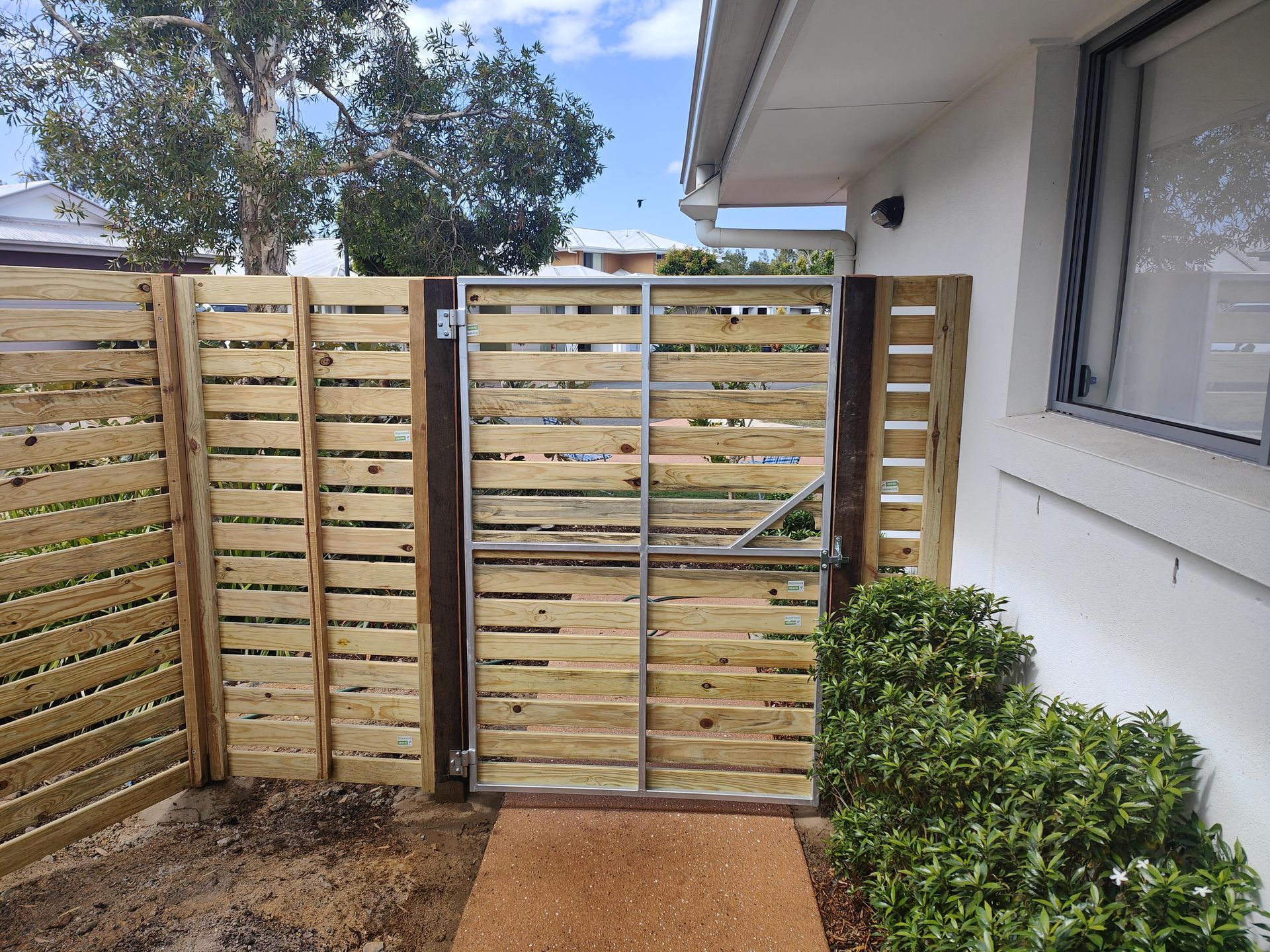 Wooden fence with a matching gate, near a white building with a window — Quality Fences 4 U in Gympie, QLD