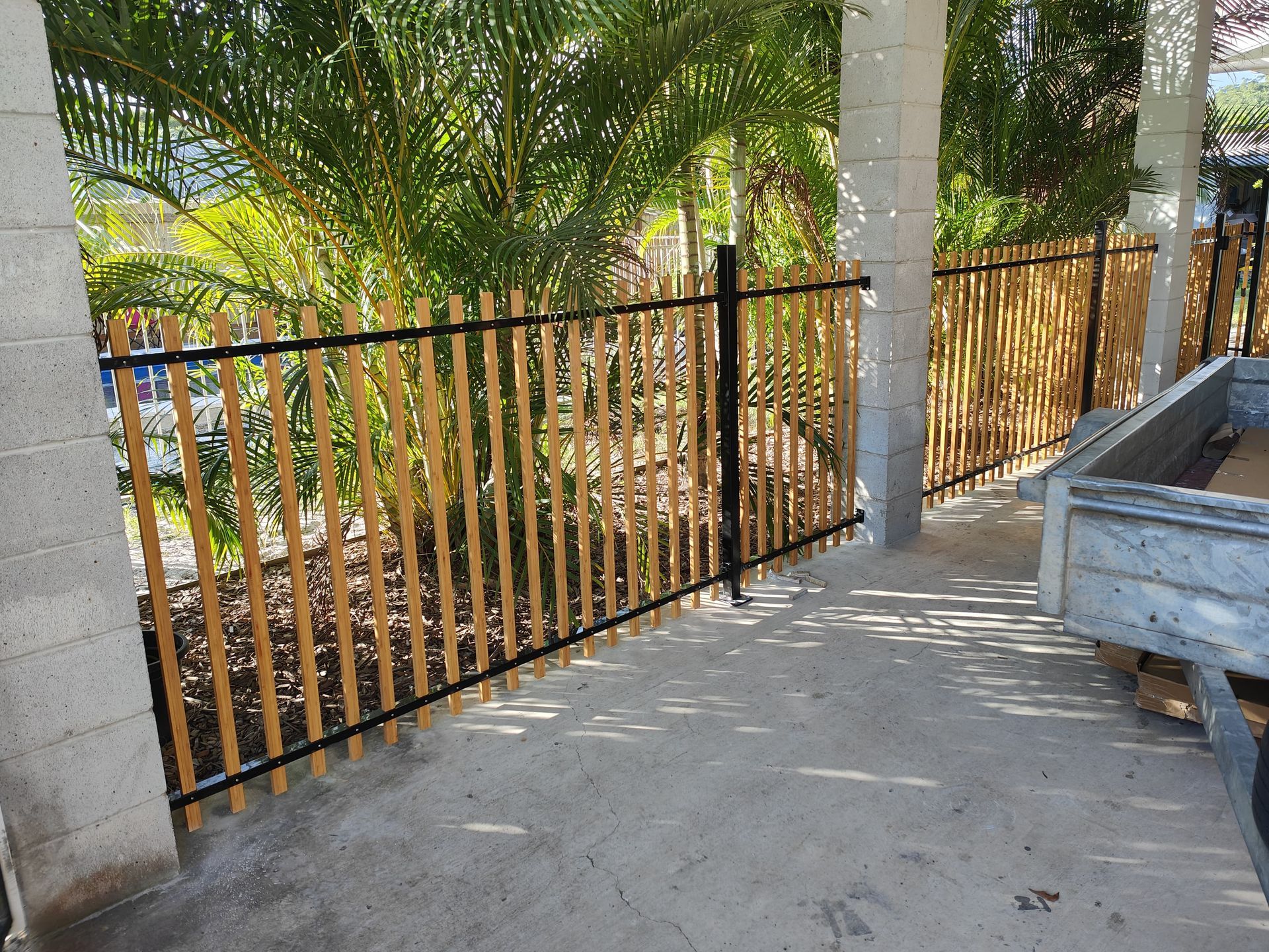 Bamboo fence with black metal frame between concrete posts, outdoors — Quality Fences 4 U in Gympie, QLD