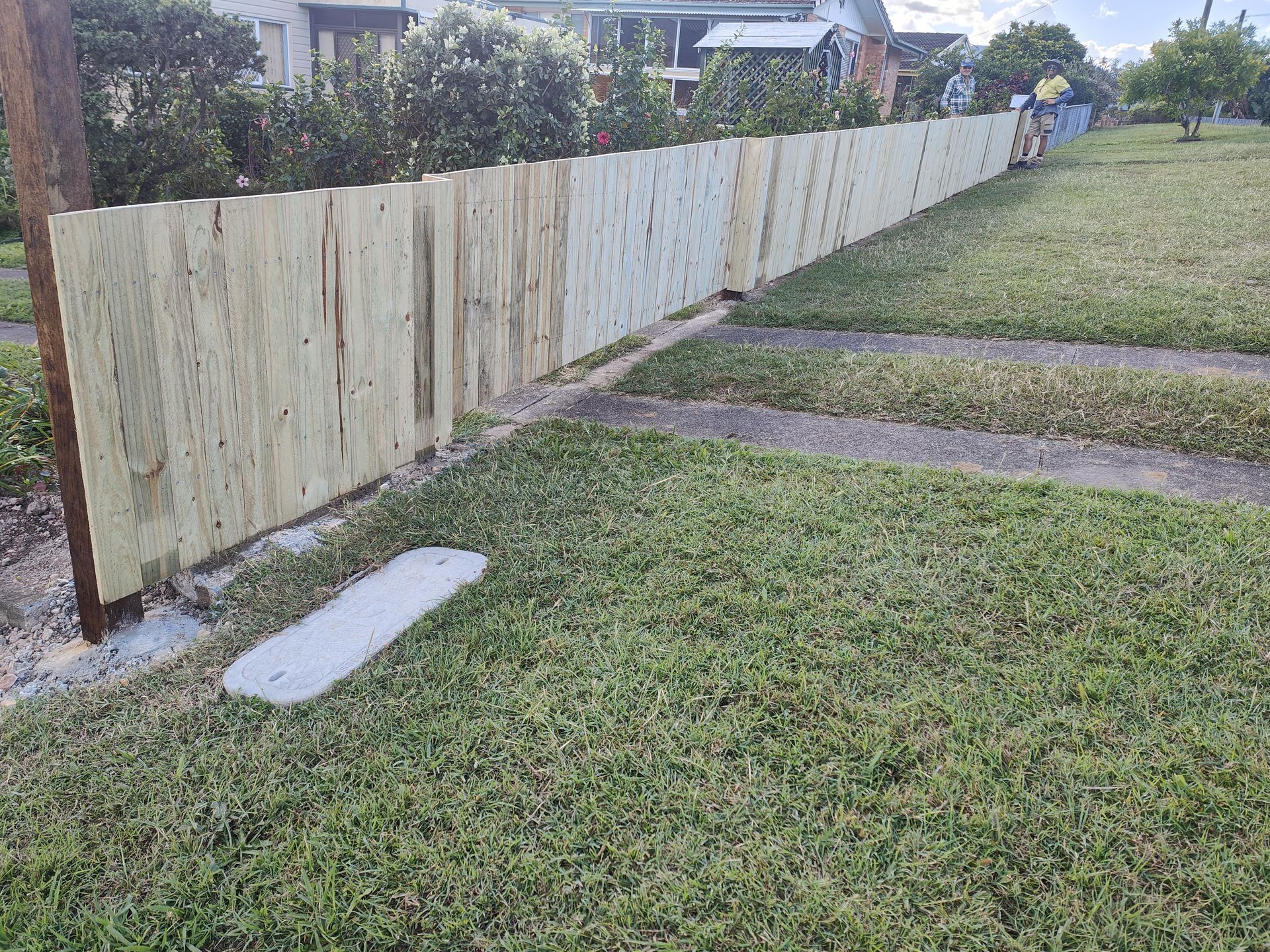 Newly constructed wooden fence bordering a grassy yard and concrete sidewalk in front of a house — Quality Fences 4 U in Gympie, QLD