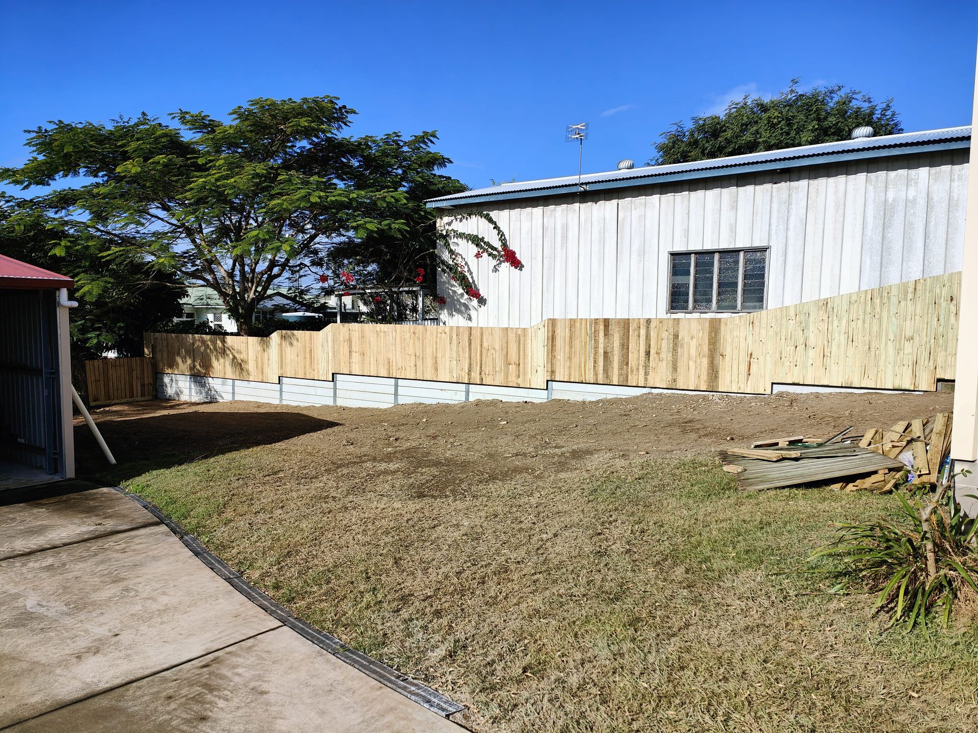 A backyard with a newly built fence, bordering a building with a tree in the background — Quality Fences 4 U in Gympie, QLD