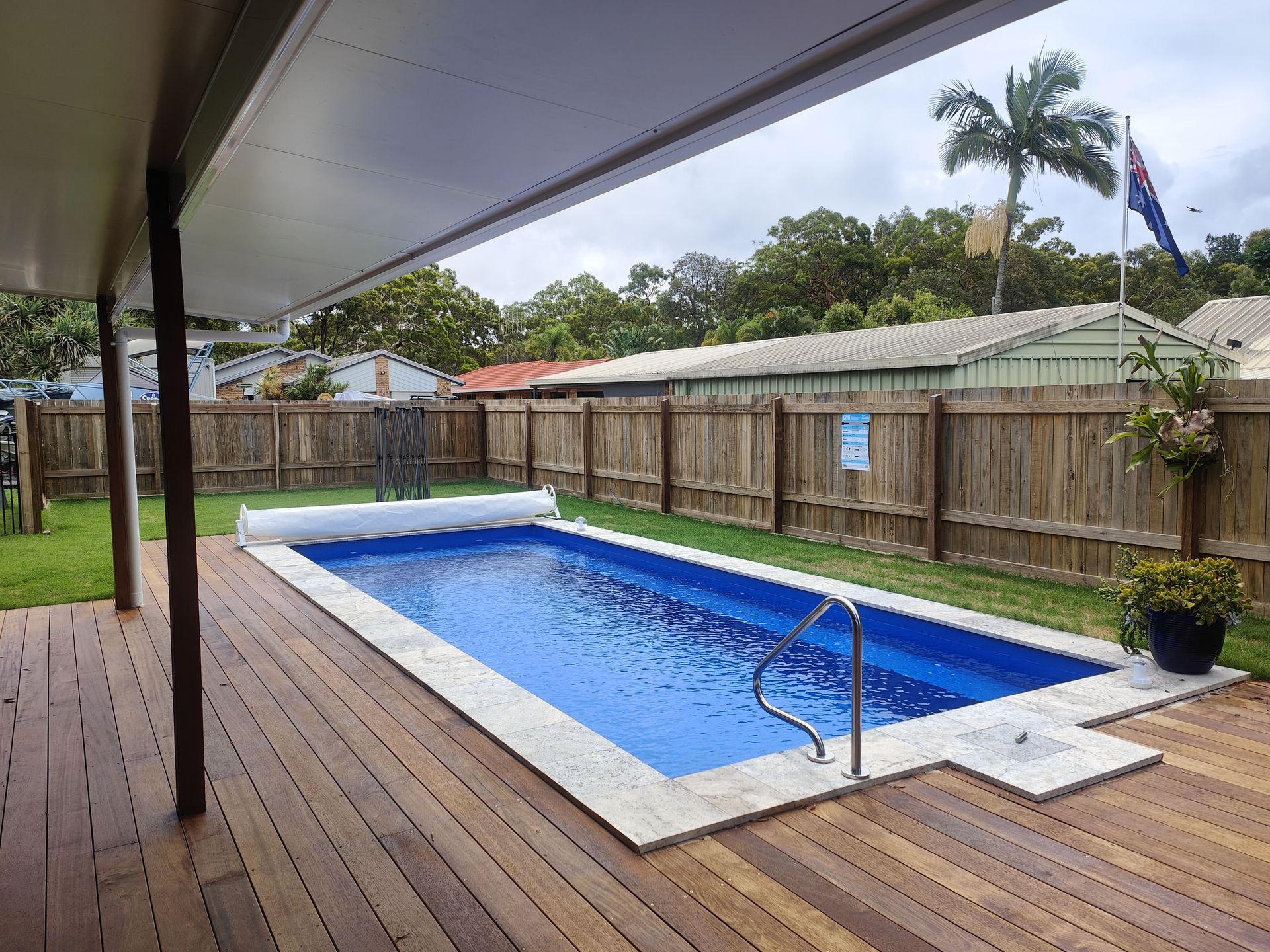 Rectangular pool with blue water and white trim, surrounded by a wooden deck and a fence — Quality Fences 4 U in Gympie, QLD